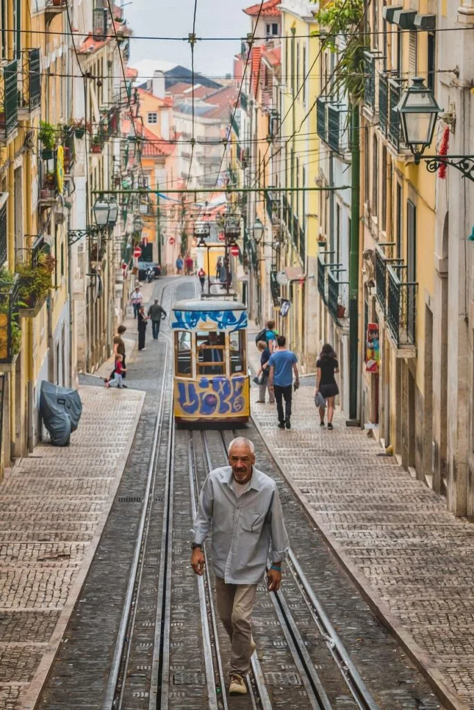 Narrow cobbled hill with yellow funicular tram and pedestrians in Lisbon street