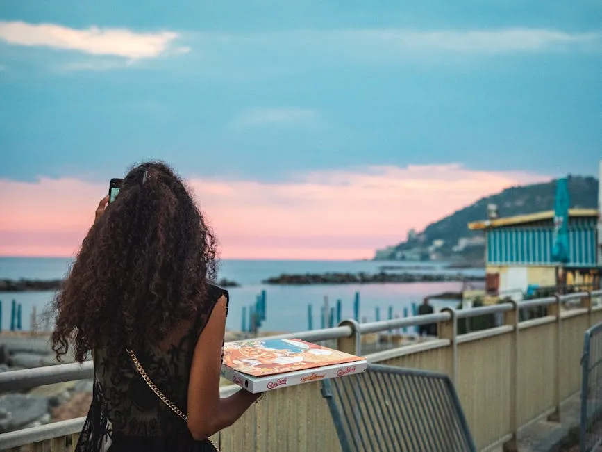 Person holding pizza box facing the Atlantic at Foz do Douro sunset.