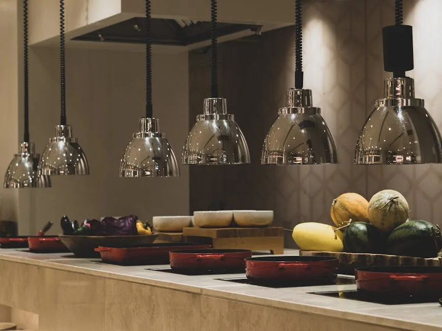 Polished metal heat lamps hanging over buffet counter with melons.