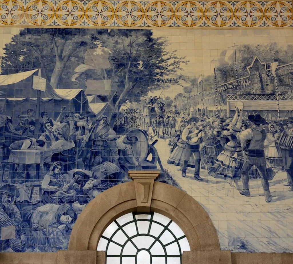 Blue azulejo tile mural depicting historical scenes above arched window at São Bento, Porto
