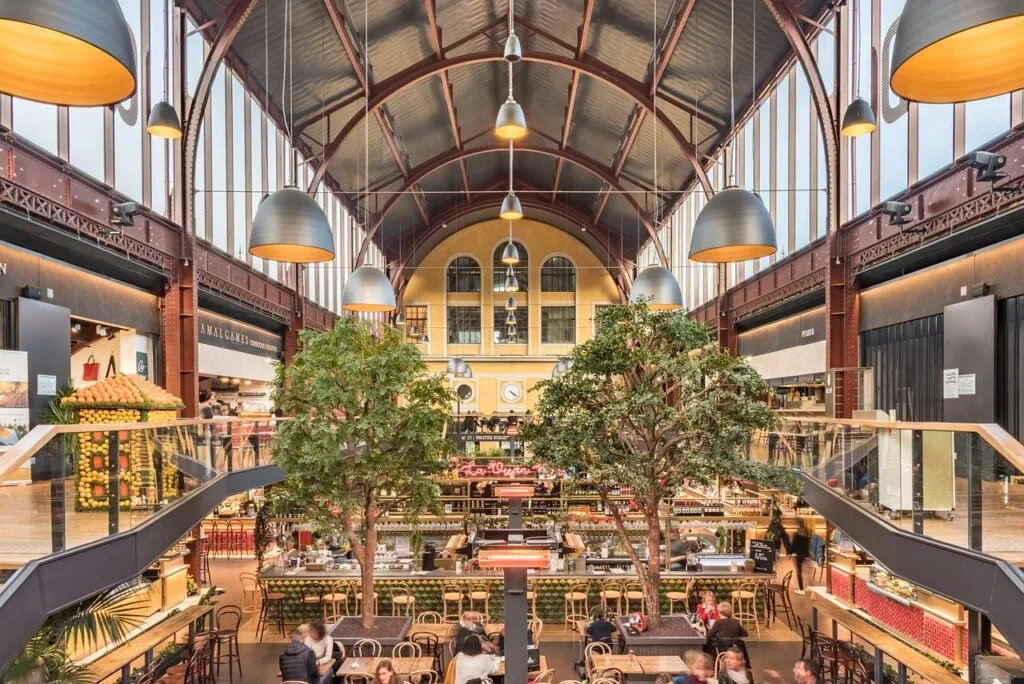 Indoor food hall stalls and people dining at Mercado Bom Sucesso