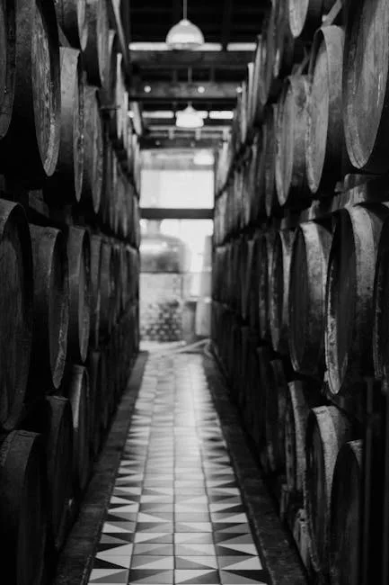 Monochrome aisle of stacked wine barrels and patterned tiled floor in Porto