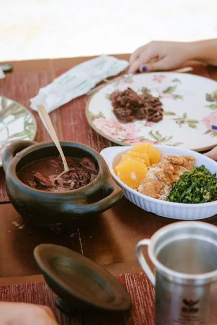 Clay pot of dark stew with oranges and greens on wooden table