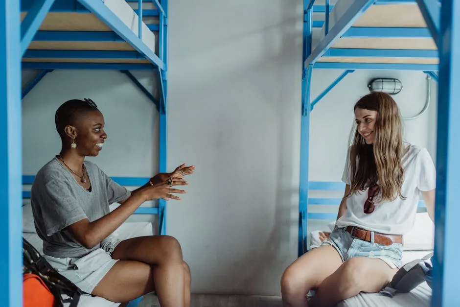 Two travelers chatting on blue bunk beds inside a Porto hostel dorm