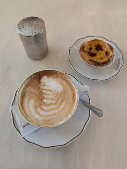 Cup of cappuccino with pastel de nata on table in Porto café