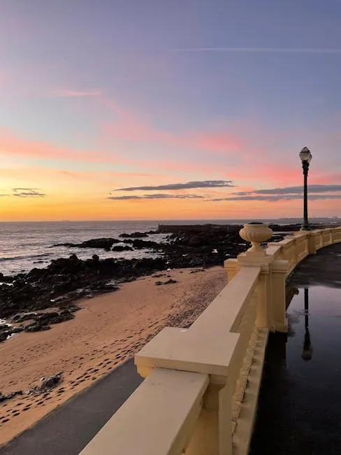 Sunset along Foz do Douro promenade with lampposts and rocky beach