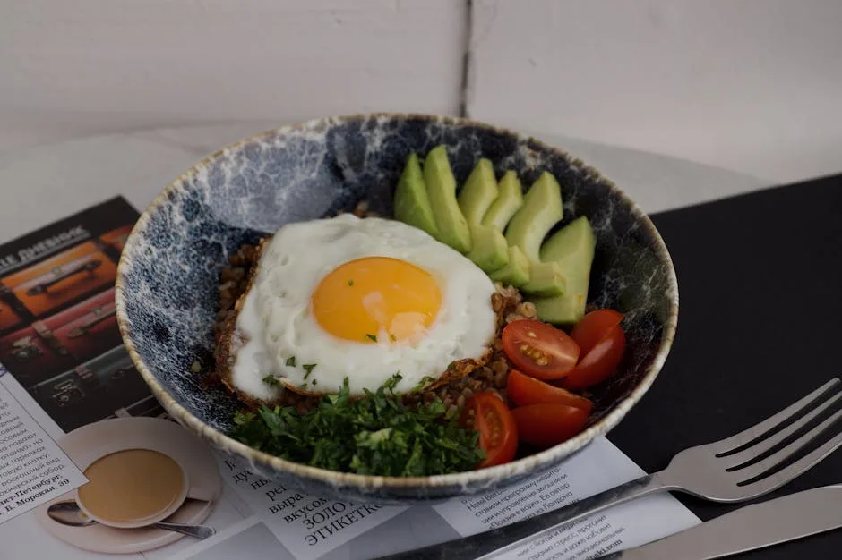 Bowl with fried egg, sliced avocado and cherry tomatoes