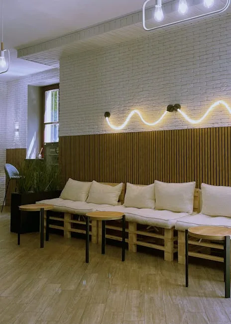 Minimal hostel lounge with pallet seating and squiggly neon light
