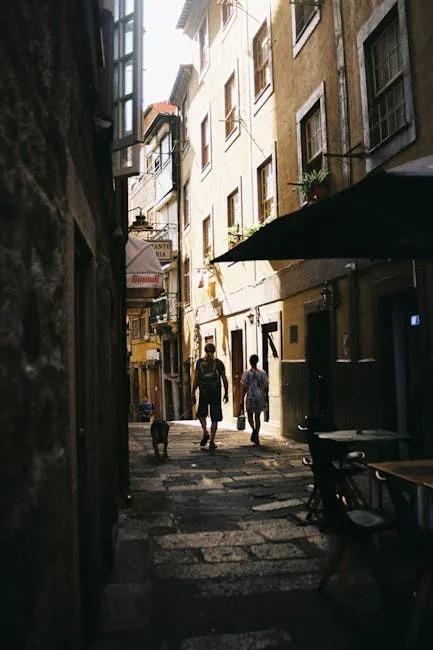 People walking a dog along a sunlit narrow street in Porto
