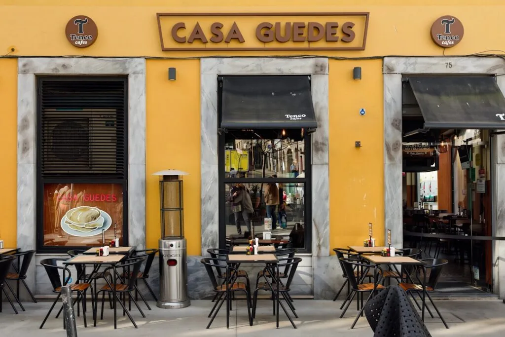 Yellow Casa Guedes café façade with outdoor tables in Porto