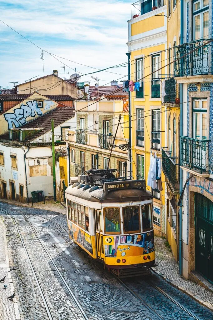 Historic yellow tram climbing a steep cobbled street among colorful buildings