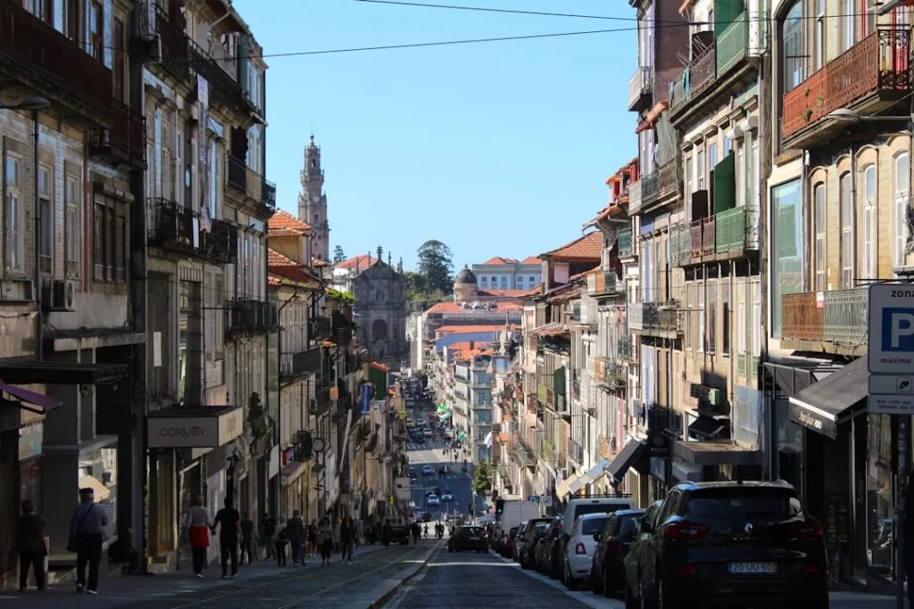 Steep Porto street lined with buildings and Clérigos Tower in distance