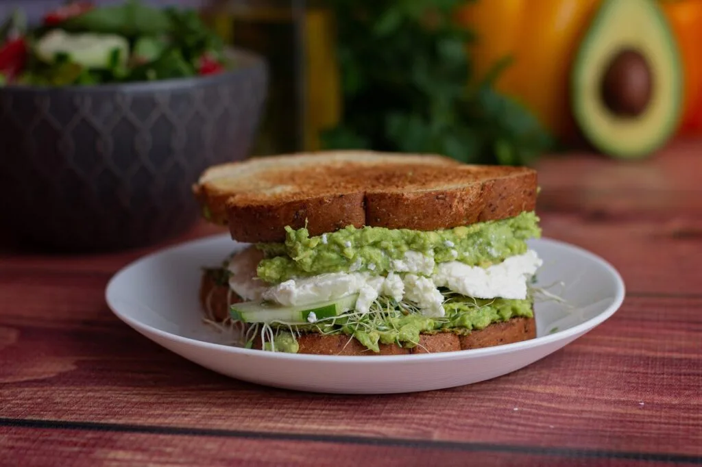 Toasted sandwich layered with mashed avocado and soft cheese