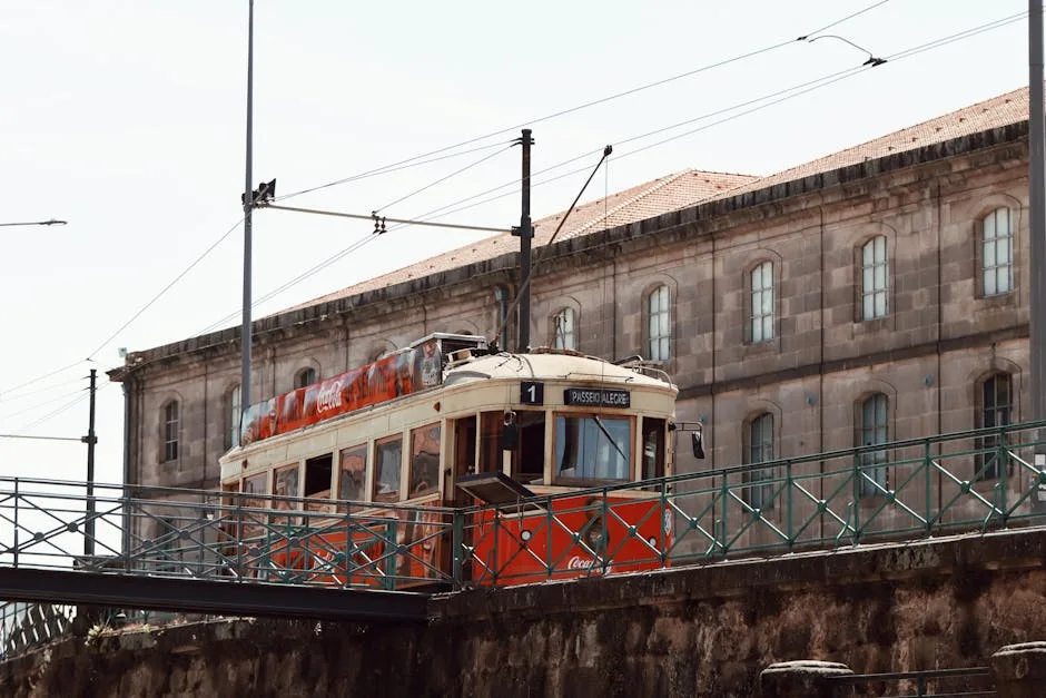 Vintage red tram crossing a metal bridge near Porto waterfront