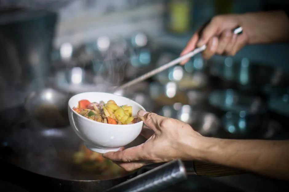 Chef ladling steaming vegetable stew into a bowl in a Porto kitchen