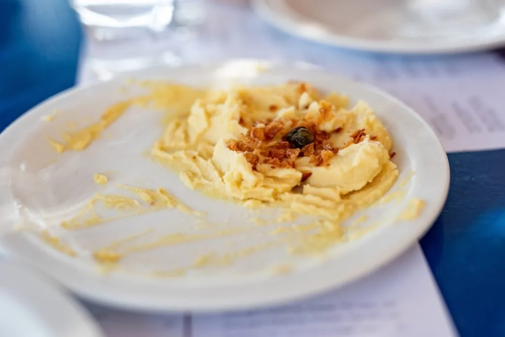 Partially eaten plate of creamy mashed potatoes topped with fried onions