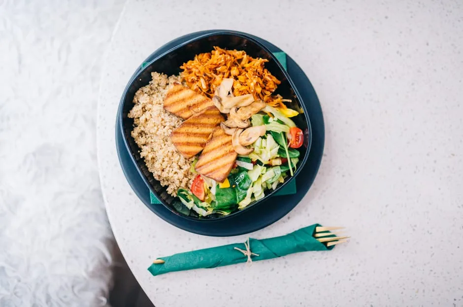 Top-down view of a veggie grain bowl with grilled tofu and salad