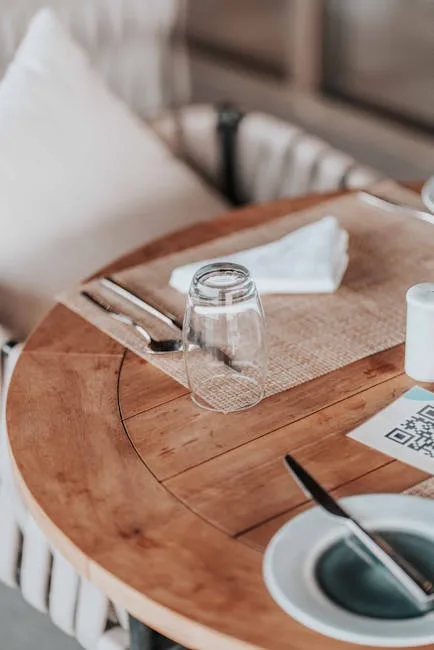 Round wooden table set with inverted glass, cutlery, and QR code.