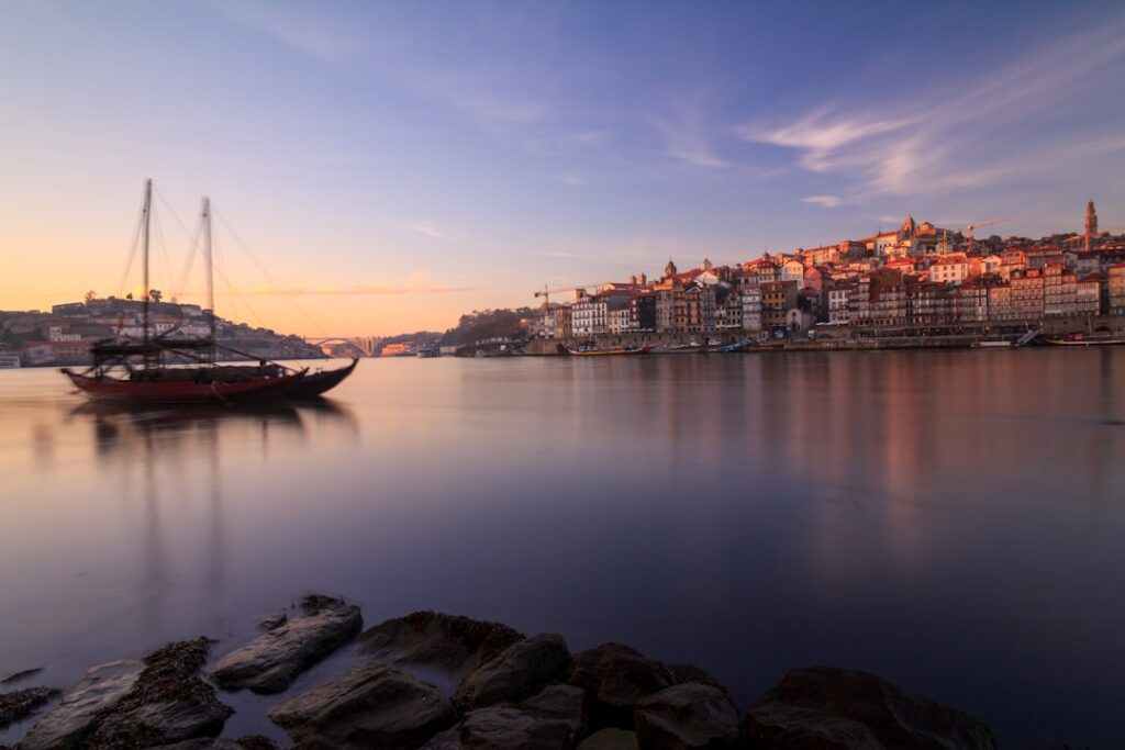 Traditional rabelo boat on the Douro with Porto's Ribeira waterfront at sunset
