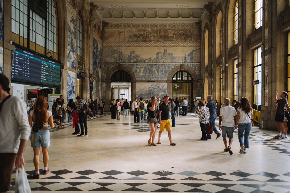 Crowded São Bento station hall with blue azulejo tile murals in Porto