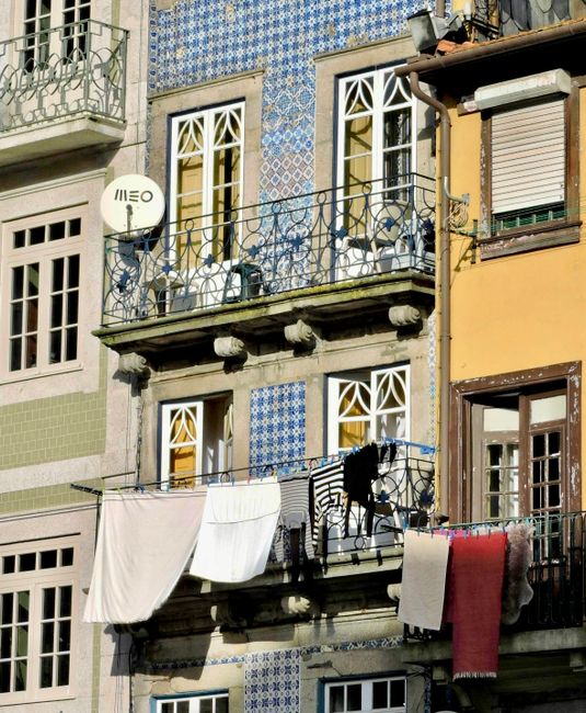 Blue-tiled Porto facade with wrought-iron balcony and drying laundry
