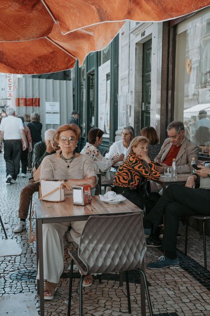 Elderly patrons seated at an outdoor cafe terrace on Porto pavement
