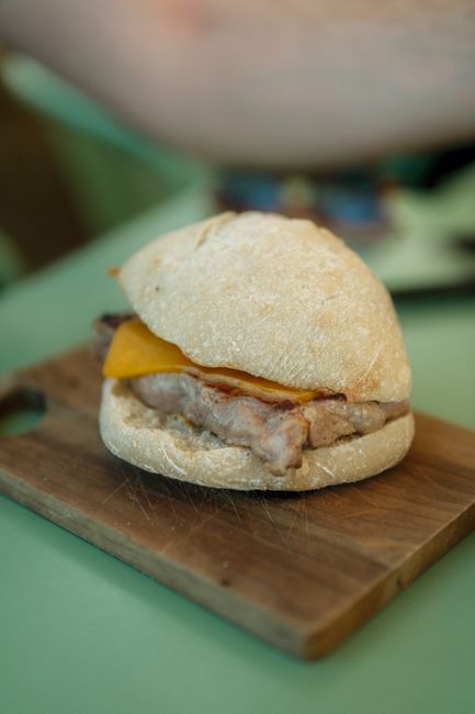 Crusty roll sandwich with meat and cheese on wooden board in Porto
