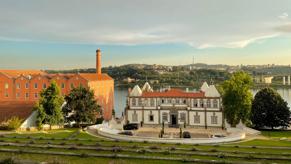 White manor with red roof and orange riverside building in Porto
