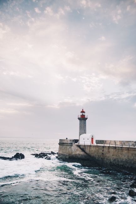 Lighthouse on a stone breakwater near Porto with rough Atlantic waves
