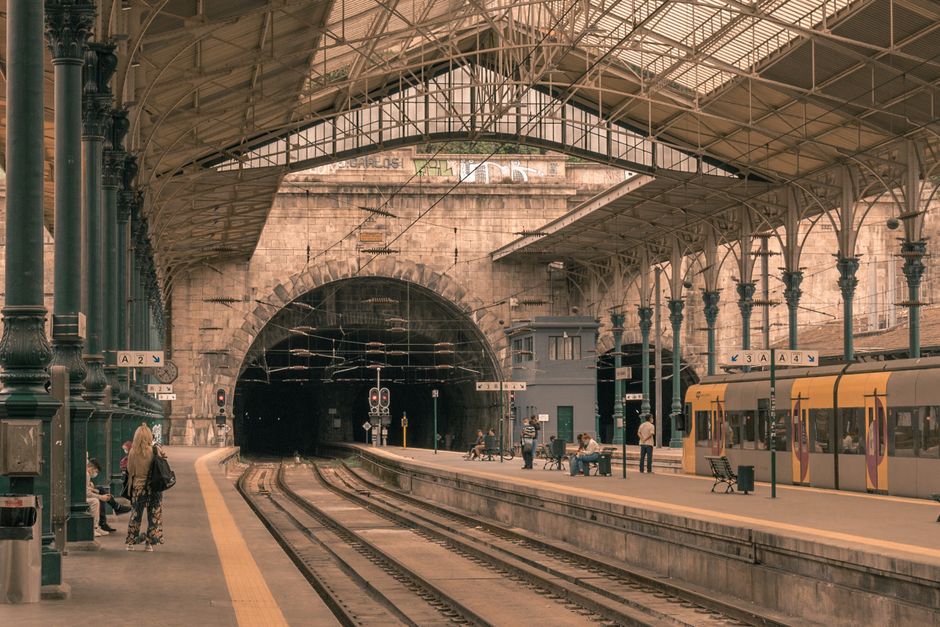 Covered train platform with ornate iron columns and tunnel entrance in Porto