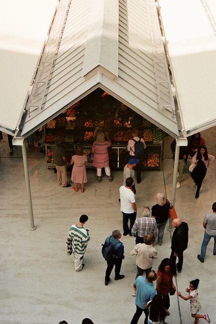 Shoppers gathered around a covered fruit stall at a Porto market