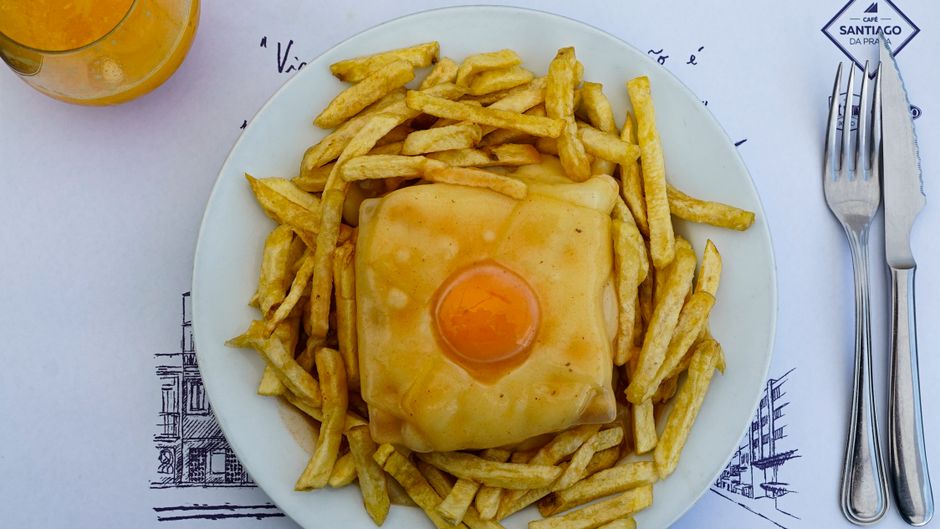 Francesinha sandwich with fried egg and fries, typical Porto dish