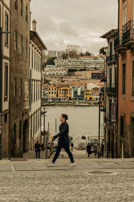 Person walking down steep Porto street toward colorful Ribeira by Douro