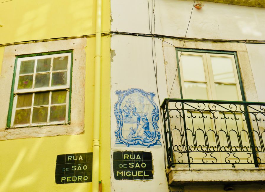 Corner of yellow building in Porto showing street signs and azulejo