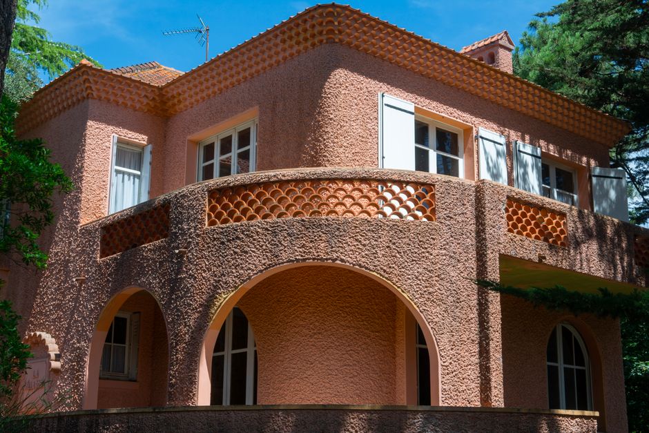 Peach-colored stucco villa with arched balcony nestled in Porto greenery