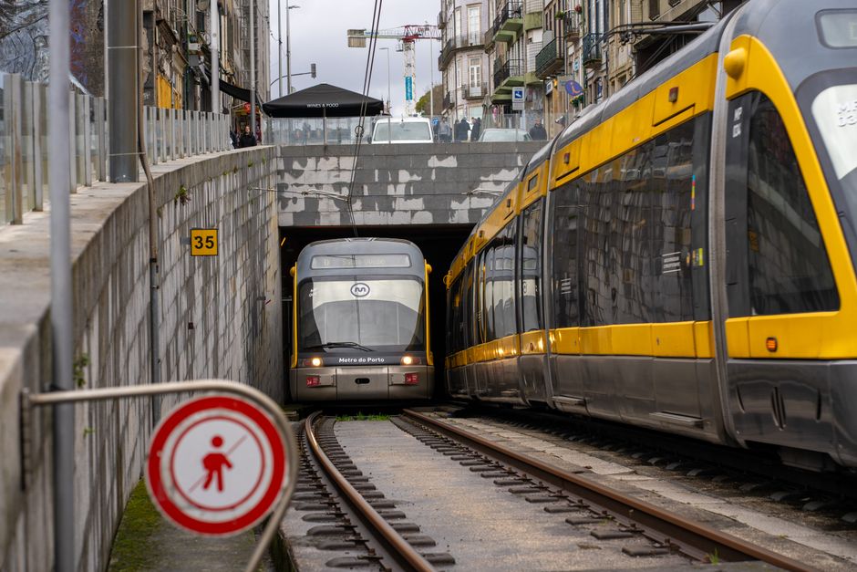 Yellow Porto metro train emerging from a tunnel on urban tracks