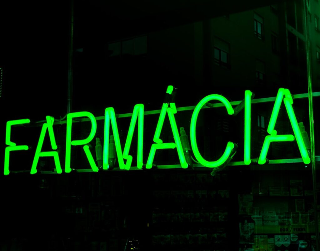 Nachtaufnahme einer portugiesischen Apotheke mit Türschild