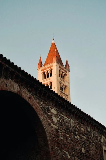 Glockenturm mit rotem Dach über einer Steinmauer in Verona