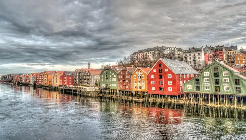 Maisons colorées sur pilotis alignées le long d'une rivière, reflet calme.