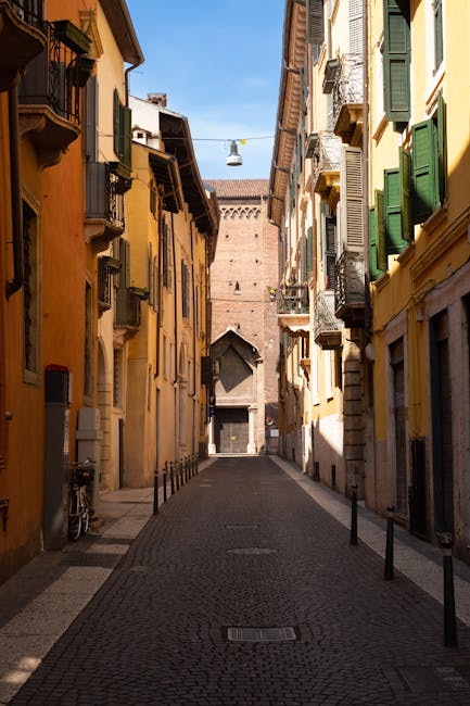 Stretto vicolo veronese lastricato con palazzi colorati e persiane verdi