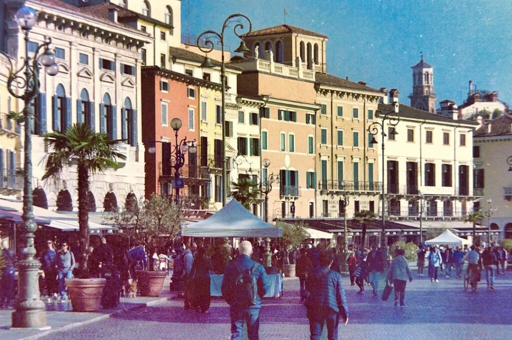 Uferpromenade mit bunten Häusern und Spaziergängern in Verona