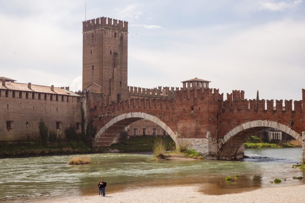 Ceglany most Castelvecchio w Weronie z wieżą i parą na brzegu