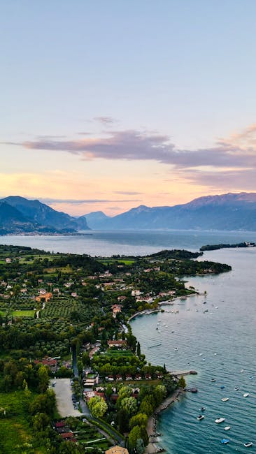 Luftaufnahme der Gardasee-Küste bei Sonnenuntergang mit Bergen und Booten