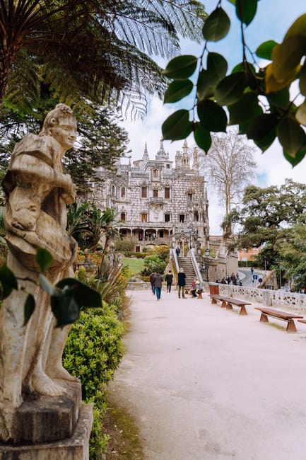 Tourists walking a decorative garden pathway at Quinta da Regaleira