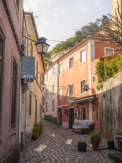 Touristen laufen tagsüber durch eine enge Gasse in Sintra