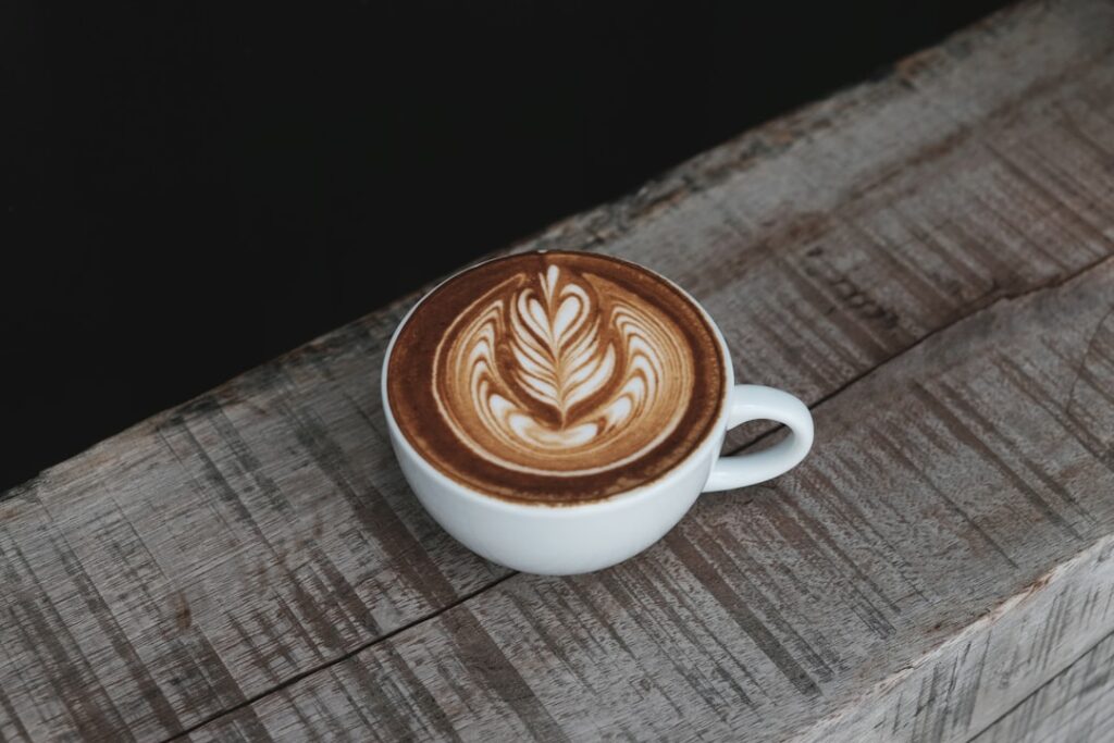 Handwerklicher Kaffee mit Latte Art auf Holztisch im Café