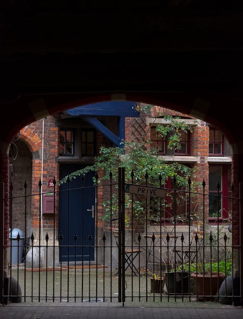 Cortile notturno con giardino nascosto dietro un cancello in legno